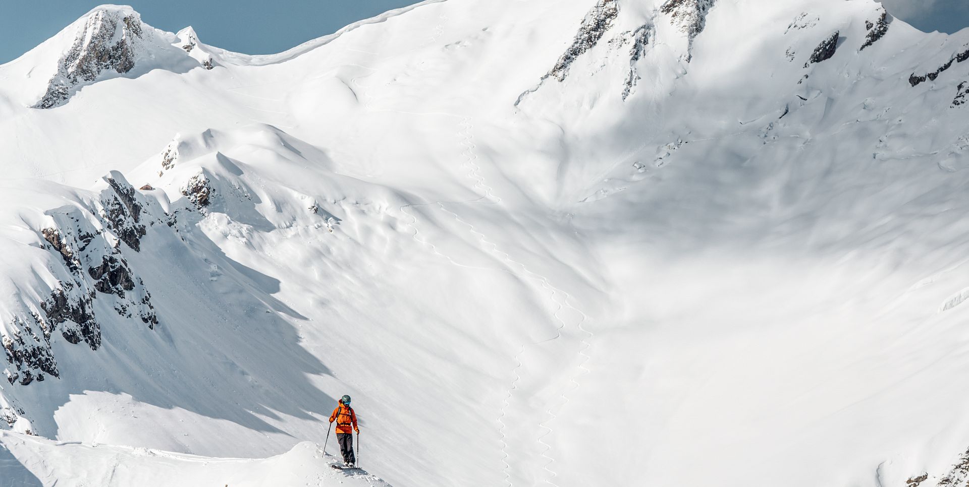 A skier stands at the start of the freeride run, surrounded by a glistening white blanket of snow.