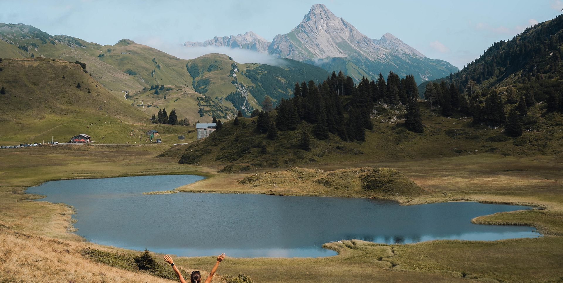 Eine Dame steht am Ufer des Kalbelesees und blickt auf den Biberkopf. Die herbstliche Landschaft breitet sich farbenfroh um sie herum aus.