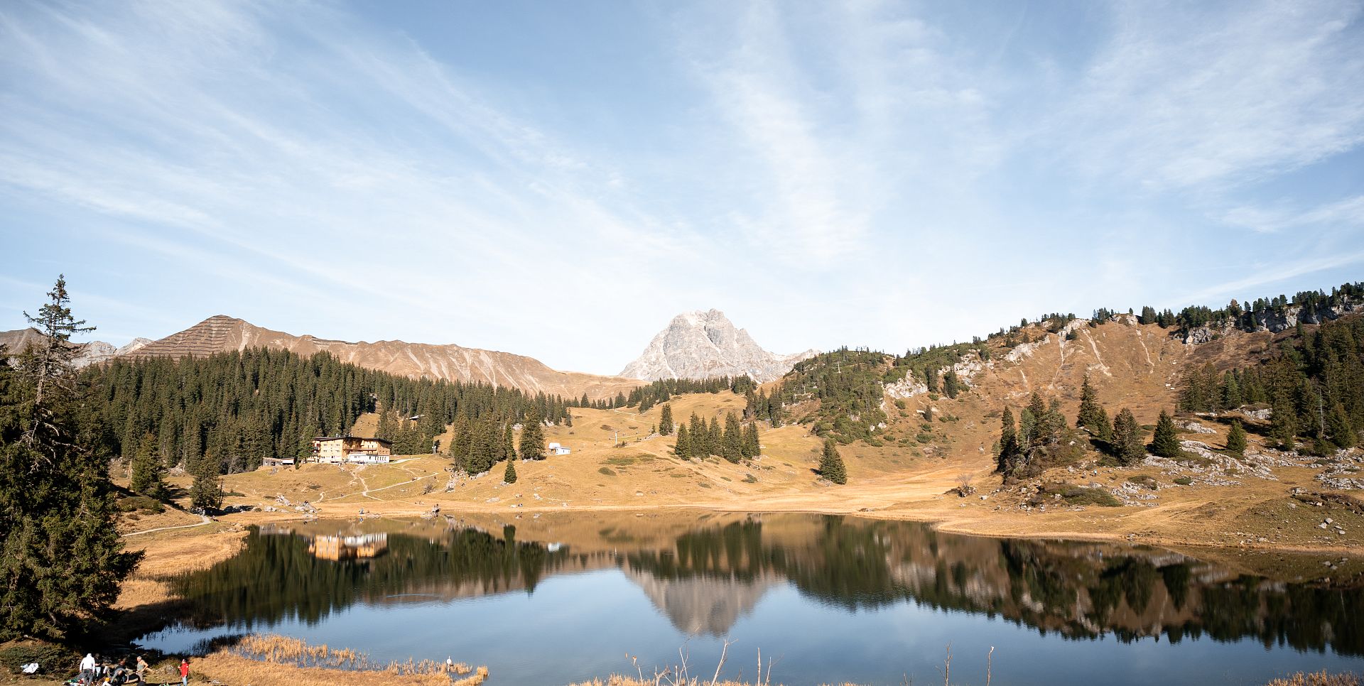 The Körbersee nestled in an autumnal landscape, with the Widderstein and the Höferspitze in the background.