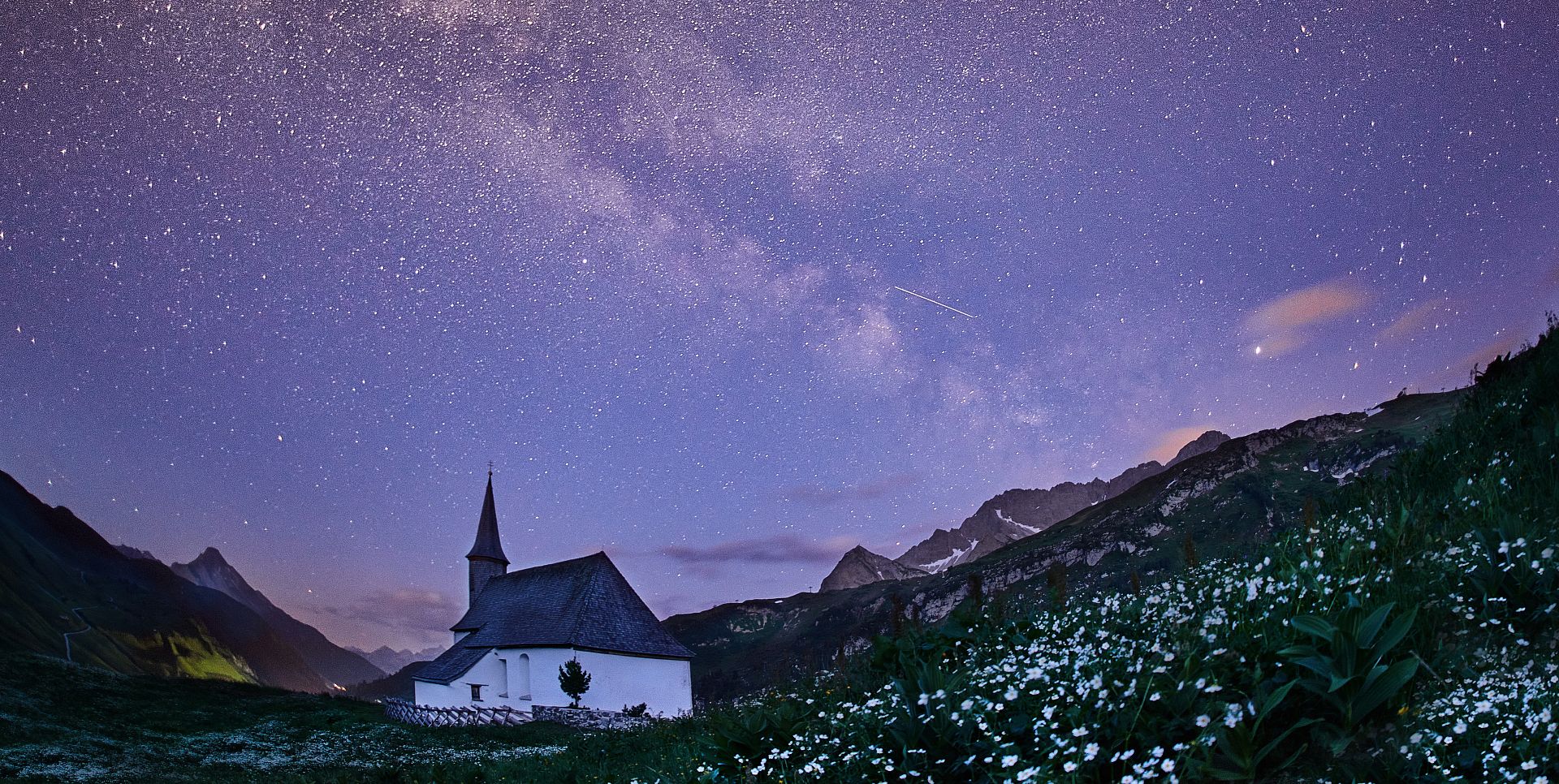 Die Simmelkapelle steht in stiller Nacht, über ihr spannt sich die leuchtende Milchstraße.