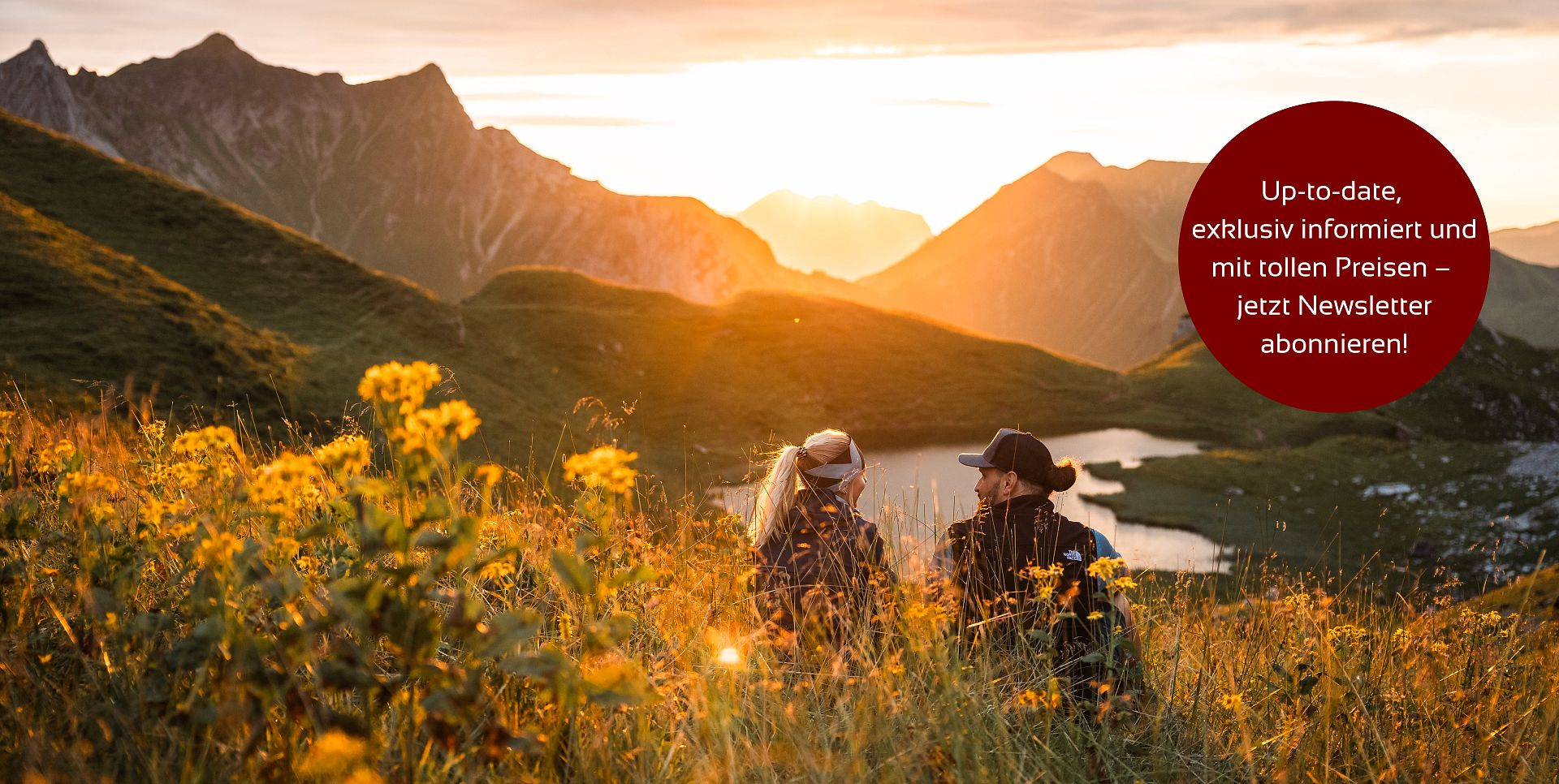 Zwei Personen sitzen am Hochalpsee und bewundern den Sonnenuntergang.
