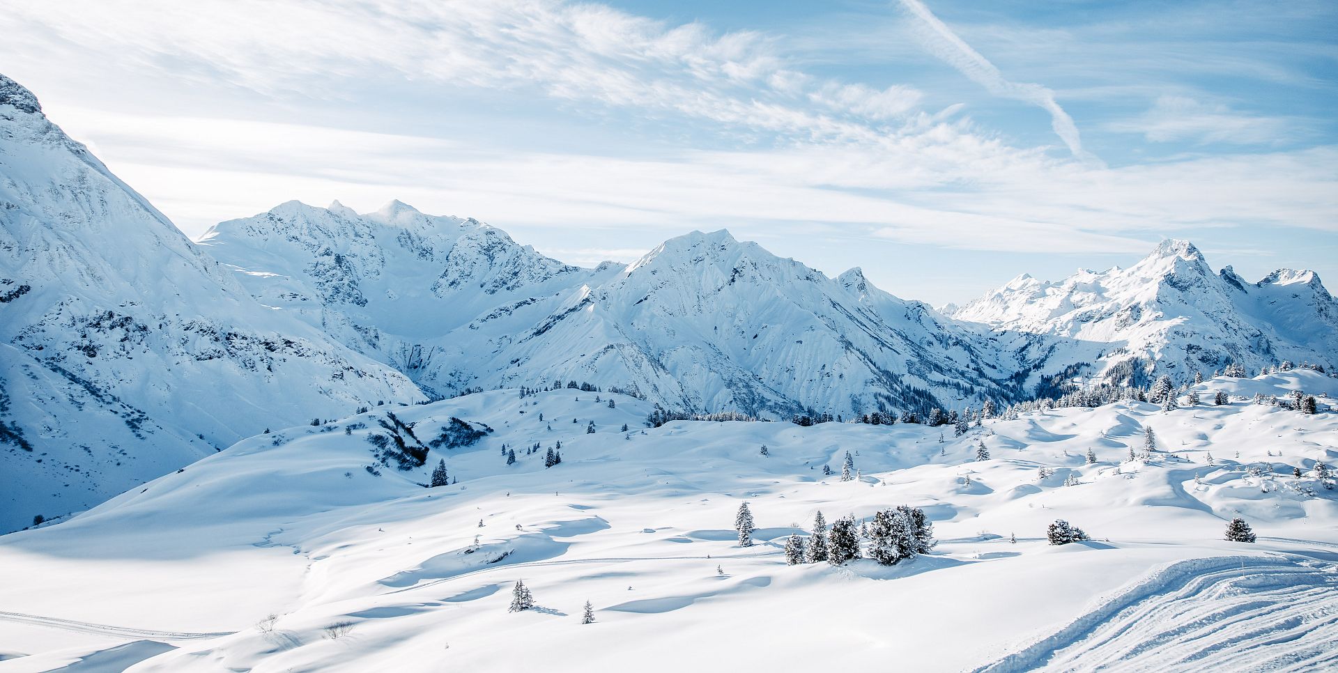 Snowy winter landscape with snow-covered trees and mountains in the background.