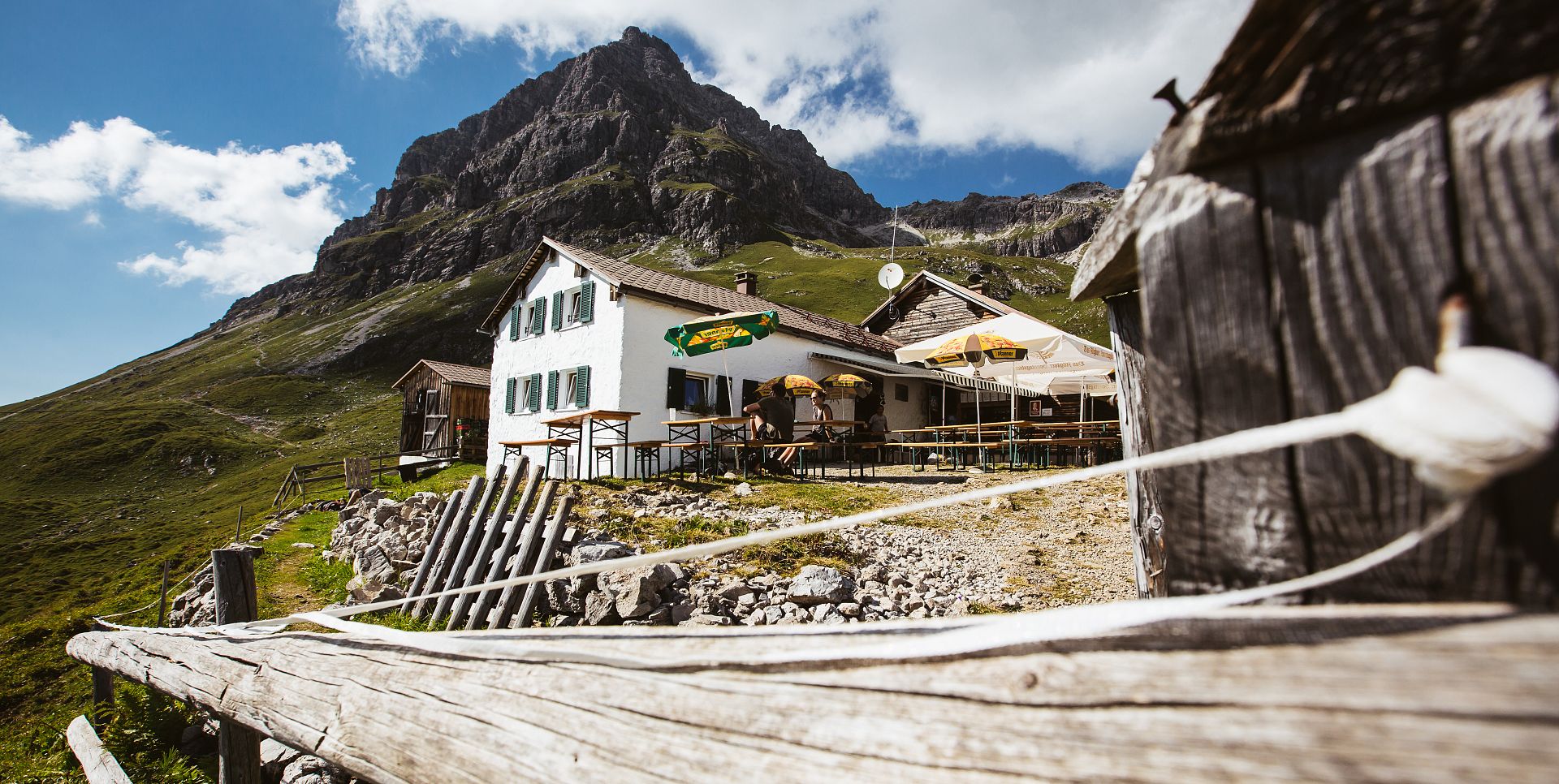 The Widderstein Hut stands behind a wooden fence, with the Widderstein rising in the background.
