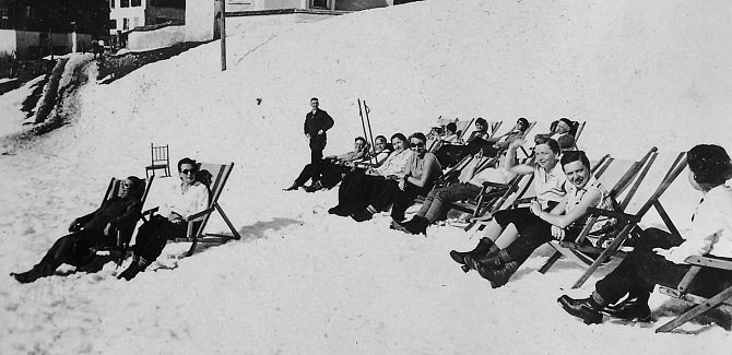 Historic photo of people relaxing in deck chairs, enjoying the sun.