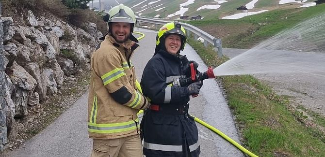 Johannes Strolz nimmt an einer Feuerwehrübung teil und hält zusammen mit einer Kollegin den Feuerwehrschlauch.