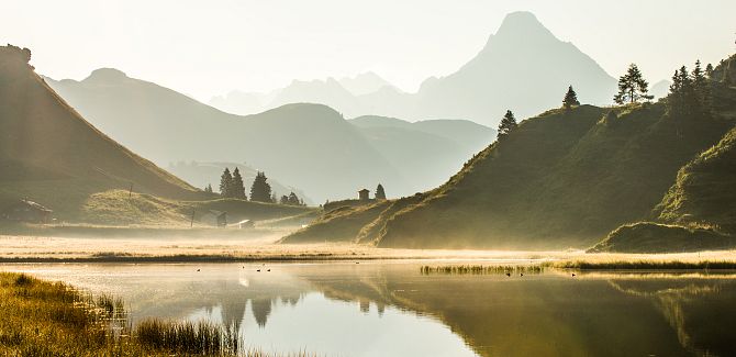 Kalbelsee lies nestled in a colorful autumn landscape, with Biberkopf rising in the background.