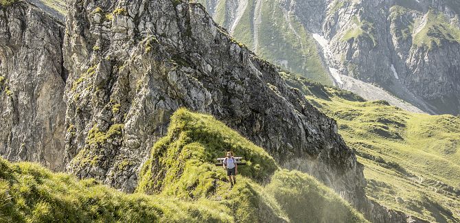 A man hikes up a grassy ridge.
