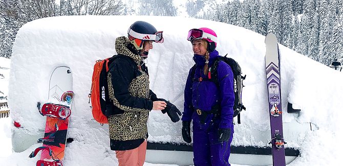 Zwei Damen stehen vor ihrem zugeschneiten Auto.