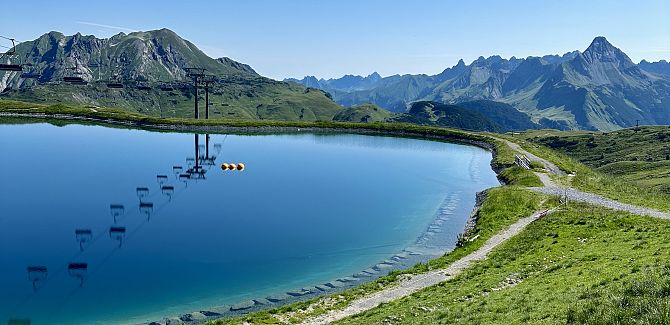 Panoramasee mit dem Biberkopf im Hintergrund und der Hochalpbahn darüber.