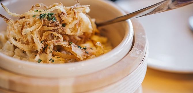 Kässpätzle are served in a rustic wooden bowl.