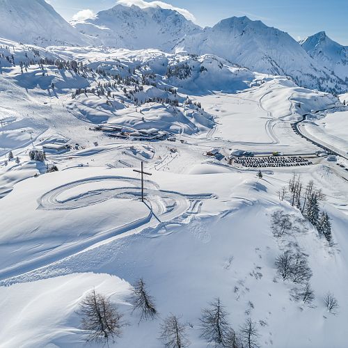Verschneite Landschaft am Hochtannbergpass, mit dem Weltfriedenskreuz am Simmel und dem Saloberparkplatz.