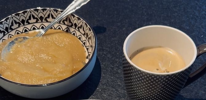 Apfelmus in einer Schale angerichtet, daneben steht eine Tasse Kaffee.