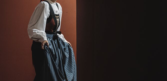 Eine Frau in Walsertracht hält ihre Schürze vor sich.