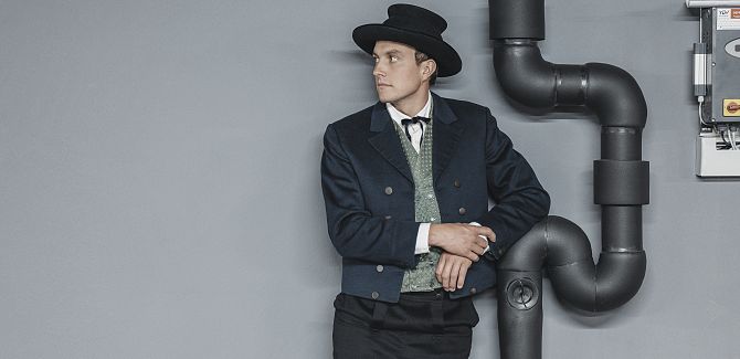 A man in Walser costume leaning casually against a pipe.