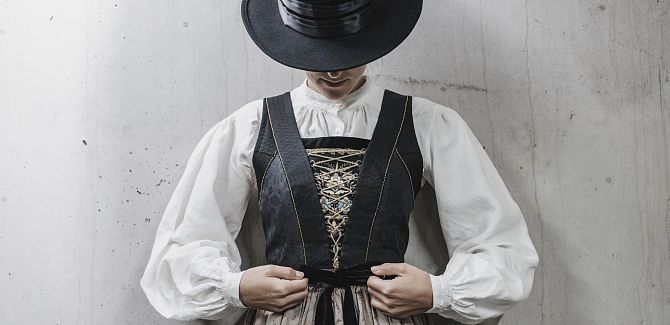 A woman in Walser costume ties her apron around her waist.