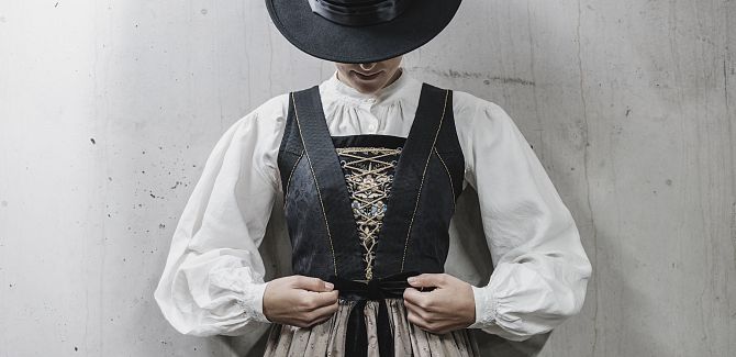 Eine Frau in Walsertracht knotet ihre Schürze um die Taille.
