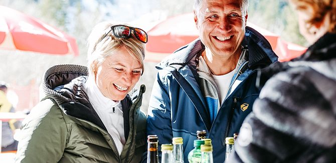 Two people are picking up a tray of drinks from the 6er Bar.