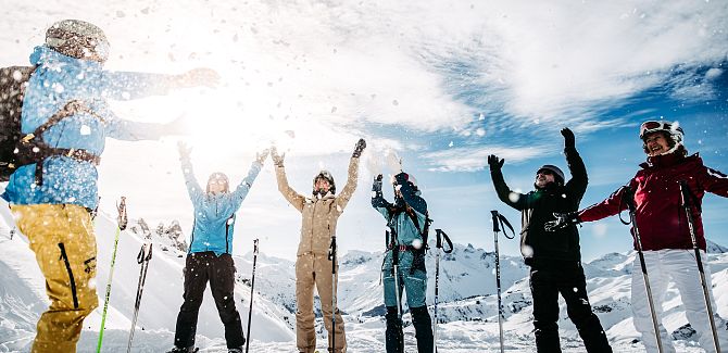 A group joyfully throws snow into the air.