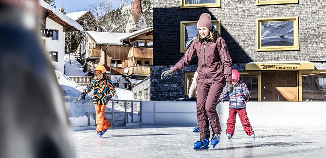 A woman is ice skating with two children.
