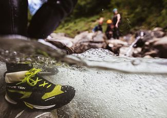 Nahaufnahme eines Schuhs beim Canyoning im fließenden Wasser.
