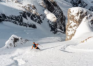Freerider Martin Winkler fährt durch den Pulverschnee und schlängelt sich zwischen Felsen hindurch.