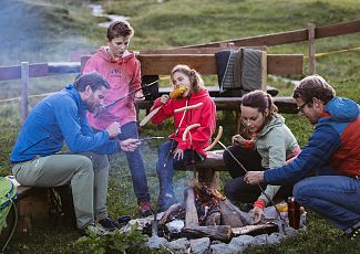 At the Jägeralp barbecue area, a family enjoys the crackling fire and their time together in nature.