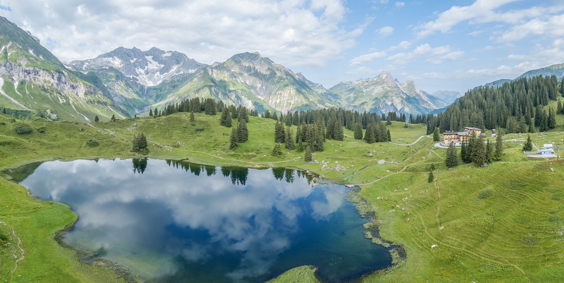Der Körbersee, in dessen Wasser sich die Wolken spiegeln, daneben das Berghotel Körbersee.
