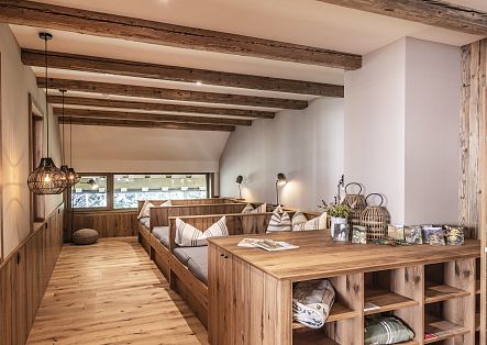 Ein heller Gastraum im alpenländischen Stil mit Holzverkleidung, Sitzbänken und großen Fenstern.