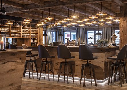 Eine moderne Holzbar in einem Restaurant mit beleuchteten Thekenelementen und Barhockern.