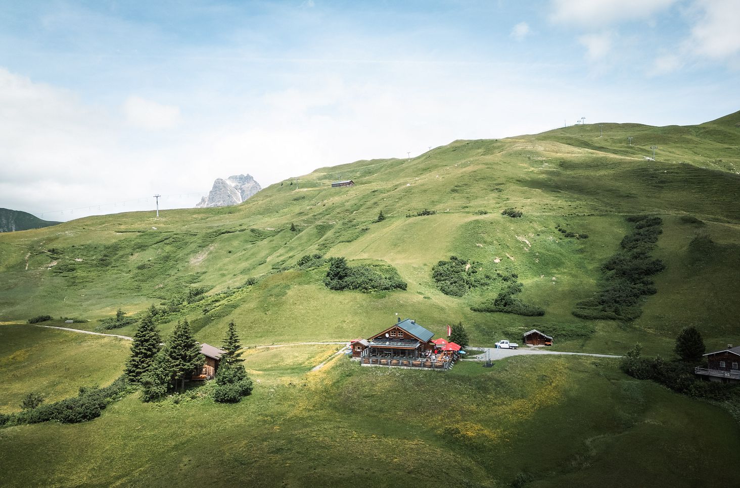 Drohnenaufnahme der Auenfelder Hütte, umgeben von einer weiten, grünen Wiese.