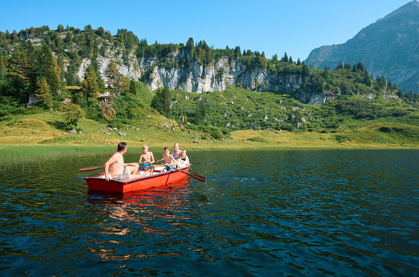 Eine Familie fährt mit einem Ruderboot auf dem Körbersee.