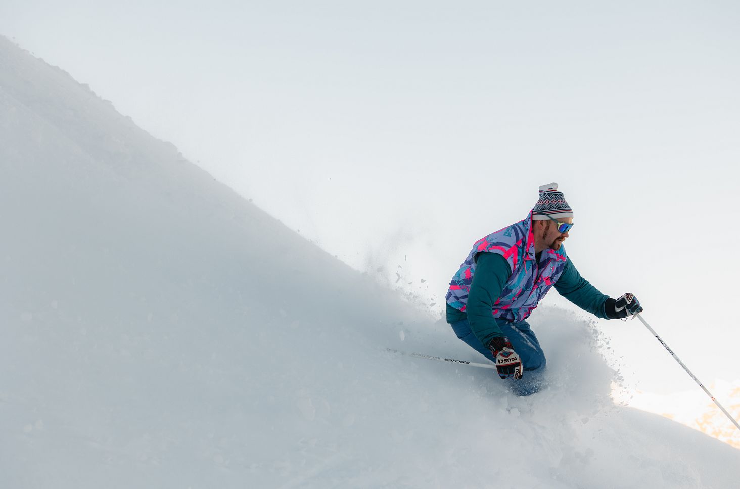 Ein Skifahrer fährt durch tiefen Pulverschnee und wirbelt dabei eine große Schneewolke auf.