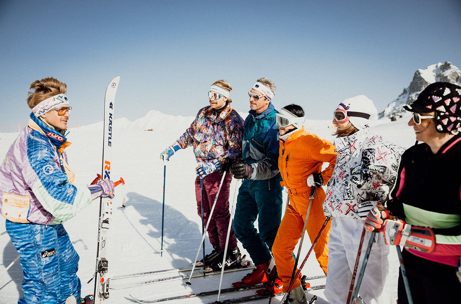 Eine Gruppe von sechs Skifahrenden steht gemeinsam auf einer verschneiten Bergfläche.