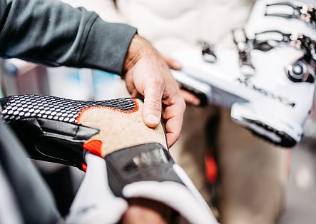 Eine Hand hält einen Skischuh während der professionellen Anpassung im Detail fest.