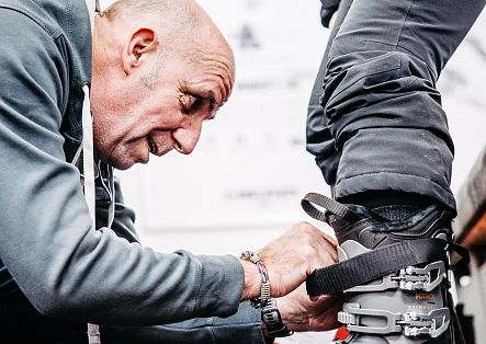 Ein Mitarbeiter arbeitet an der Schnalle eines Skischuhs, während die Kundin ihren Fuß aufstellt.