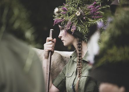 A woman working on an alp wearing a decorated hat.