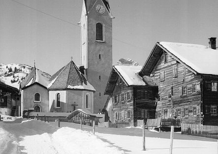 Historic photo of the church in Warth, with two old farmhouses in front.