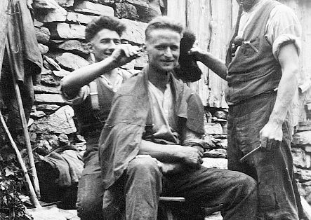 Historic photo of two men cutting another man’s hair.