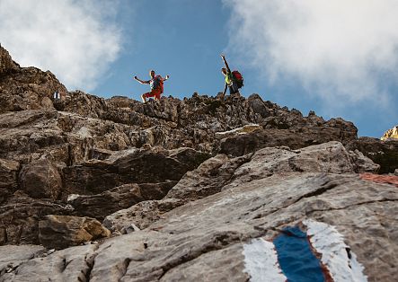 Two people climb the rocky terrain towards Widderstein, navigating by the trail markers.