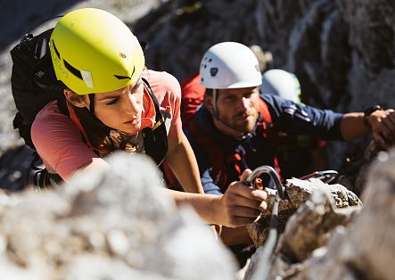 Two people on the via ferrata, close-up as they navigate the rocks.