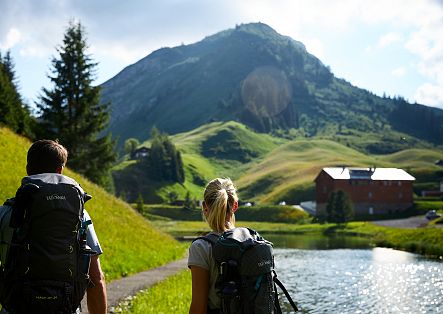 A man and a woman are looking together at the idyllic Seebachsee, surrounded by gentle hills.