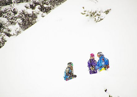 Two women and their guide stand in deep powder.