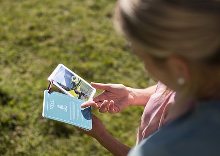 A woman is looking at a set of mindfulness cards.