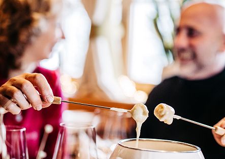 Ein Paar sitzt gemütlich im Restaurant Holzschopf und genießt ein Käsefondue.