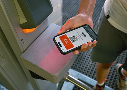 A visitor scans their digital guest card at the turnstile to access the mountain lift.