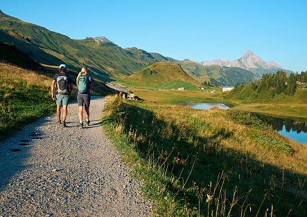 Zwei Personen wandern in Richtung Kalbelesee, im Hintergrund ist der Biberkopf zu sehen.